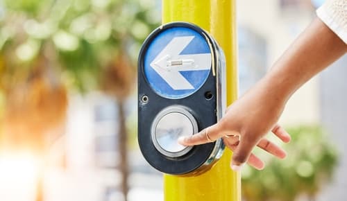 person pressing pedestrian crosswalk button