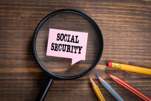 social security note on desk with magnifying glass and pencils