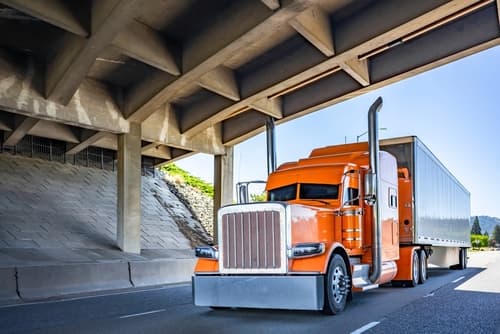 semi truck driving on road under overpass