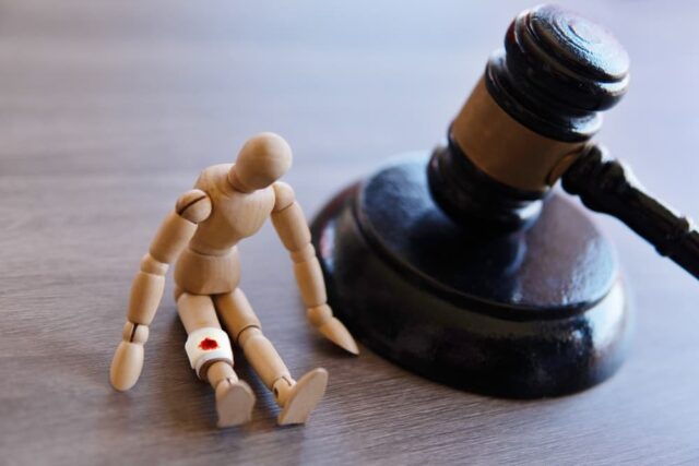 Bandage wrap with blood stain, wooden doll and judge gavel. Personal injury law concept.