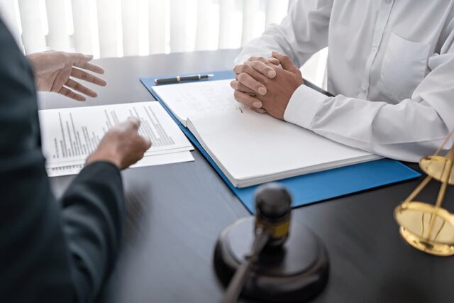 Lawyer with lawsuit meeting with client discussing with contract agreement at courtroom.