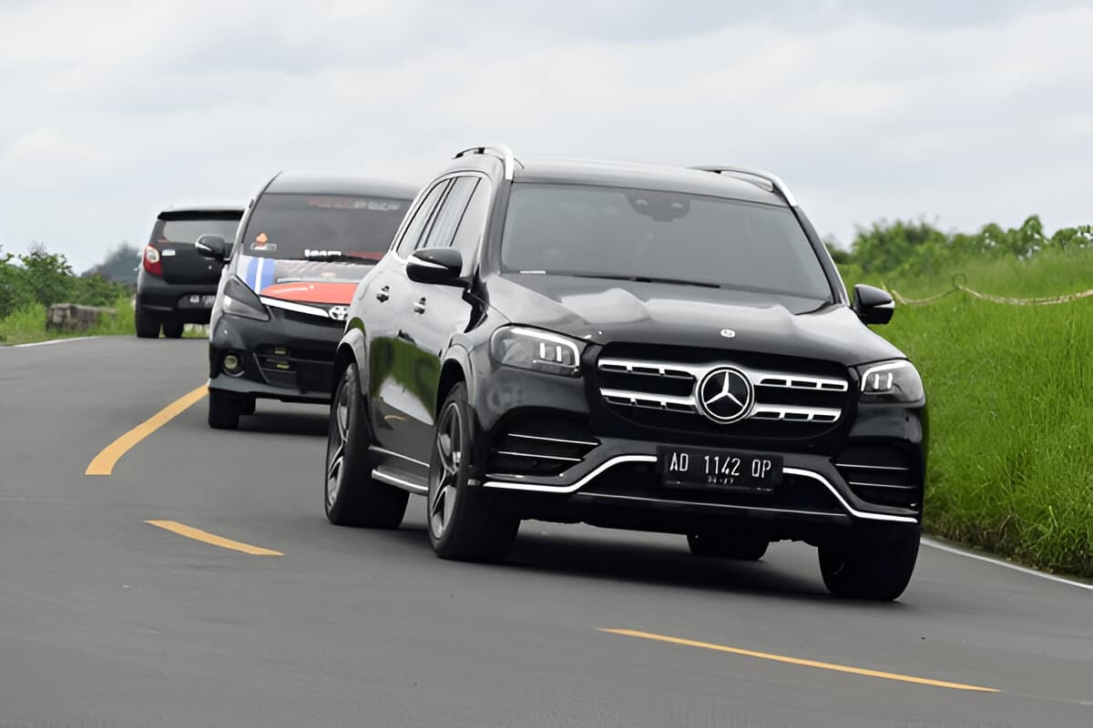 a black Mercedes-Benz GLS 450 AMG making a left turn along the asphalt road|Car accident. Young Asian woman after car accident.