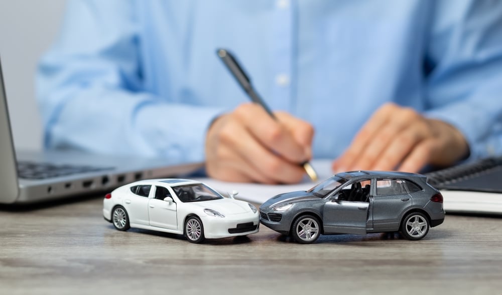 An insurance company employee prepares a paper form for a traffic accident. Legal assistance with a car accident.|n a white table there is a calculator