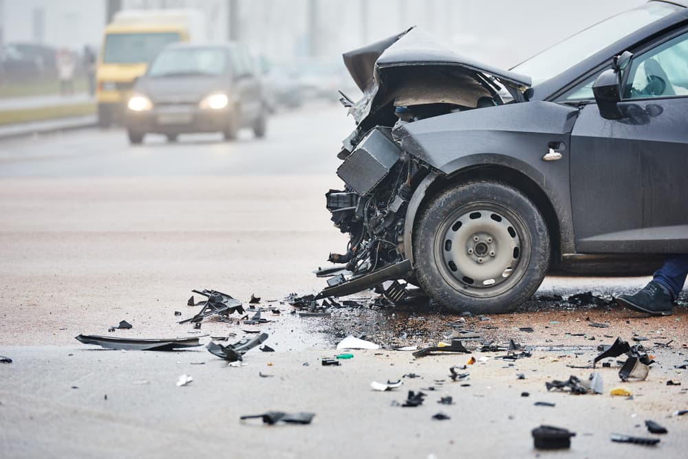 Un automóvil gris con graves daños en la parte delantera tras una colisión